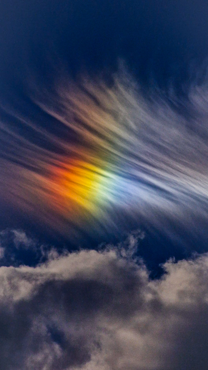 Sky photography by Tony Livins showing rainbow-like light through clouds